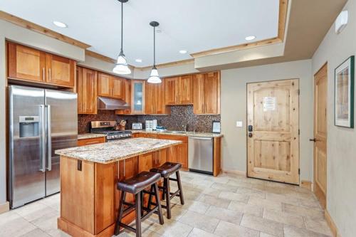 a kitchen with wooden cabinets and a island with bar stools at Luxurious Modern Condo! - SM #207 in Bear Valley