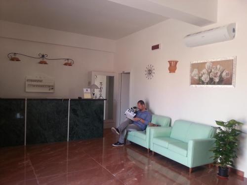 a man sitting on a couch in a living room at Agriturismo Tenuta Don Giovanni in Melendugno