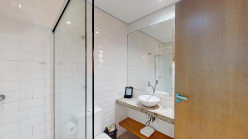 La salle de bains est pourvue d'un lavabo et d'une douche en verre. dans l'établissement Studio 3 Pinheiros by Oba, à São Paulo