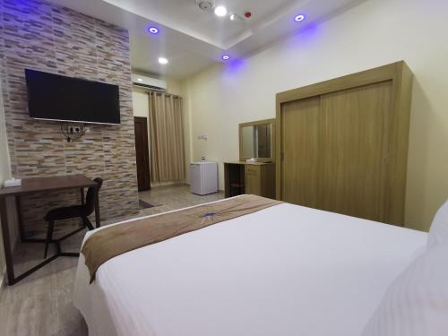 a bedroom with a bed and a tv on a brick wall at Sohar Hotel - فندق صحار in Sohar
