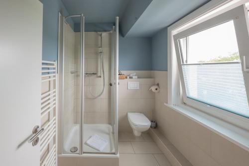 uma casa de banho com um chuveiro, um WC e uma janela. em Hotel 'Das Strandhaus' em Sankt Peter-Ording