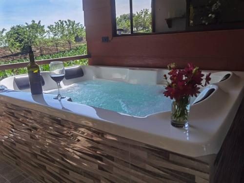 a bath tub with a bottle of wine and a glass at Howler's House in Chachagua