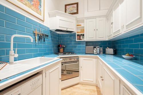 niebieska kuchnia z białymi szafkami i zlewem w obiekcie JOIVY Elegant 1 bed flat in Chelsea w Londynie