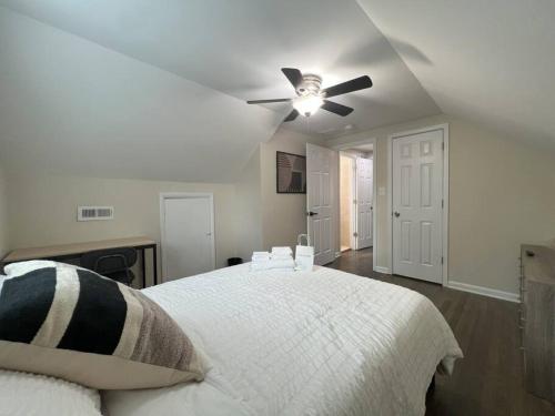 a bedroom with a white bed with a ceiling fan at The Castilian by Keywee Rentals in Manassas