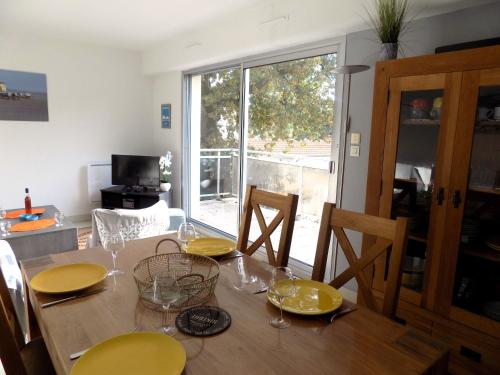 uma sala de jantar com uma mesa com pratos e copos amarelos em Royan Quartier du Parc - APPARTEMENT proche PLAGE et COMMERCES - WIFI em Royan