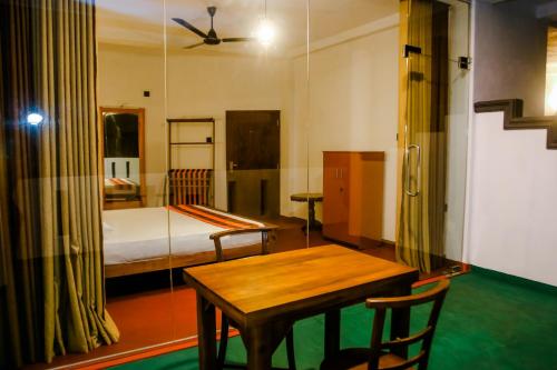 a bedroom with a bed and a wooden table and chairs at Little Angels in Mirissa