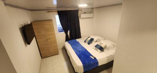 Schlafzimmer mit einem Bett mit blauer Bettwäsche und Kissen in der Unterkunft Edificio Regata INN in Buenaventura