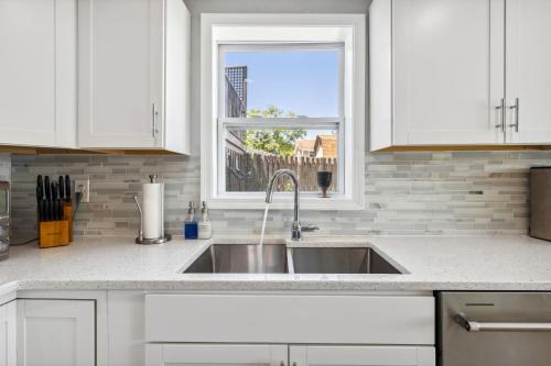 a white kitchen with a sink and a window at Landmark Lakehouse - luxury living in PLX in Akron