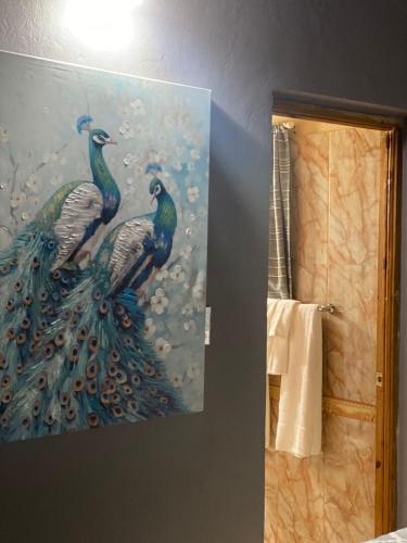 a painting of two peacocks hanging on a wall at Montego Bay, Ironshore Luxury Studio in Montego Bay