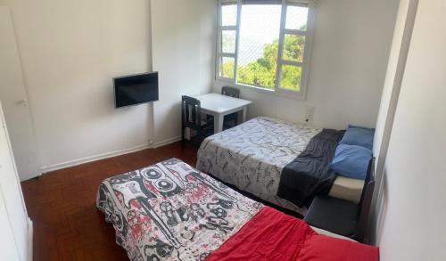 um pequeno quarto com uma cama e uma televisão em Vista Maravilhosa em São Vicente