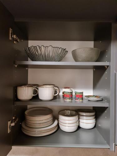 a cabinet filled with plates and bowls and utensils at ALPINA Mountain View Apartment in Špindlerův Mlýn