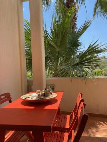 a red table with a plate of food on it at V Appartamenti in Baia Verde