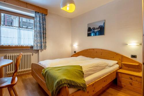 a bedroom with a wooden bed and a window at Apartment Pordoi in Campitello di Fassa
