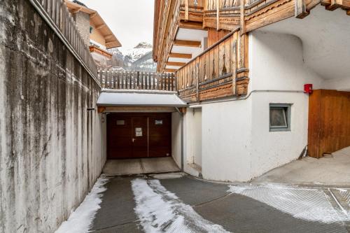 a building with a wooden door and snow on the ground at Apartment Pordoi in Campitello di Fassa