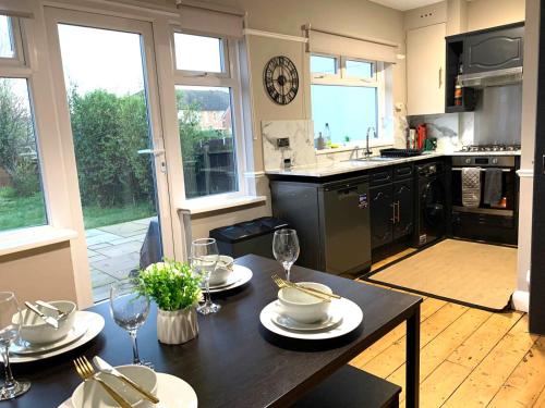 a kitchen with a table with plates and wine glasses at Cosy 3 bed house with FREE Parking near Kingston Thames in Malden