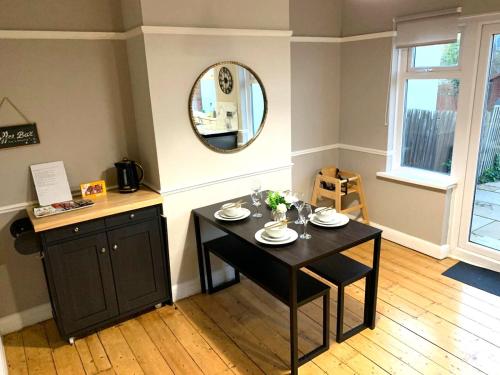 a dining room with a table and a mirror at Cosy 3 bed house with FREE Parking near Kingston Thames in Malden