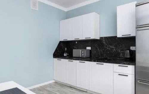 a white kitchen with white cabinets and a refrigerator at VIP apart 602 in Tbilisi City