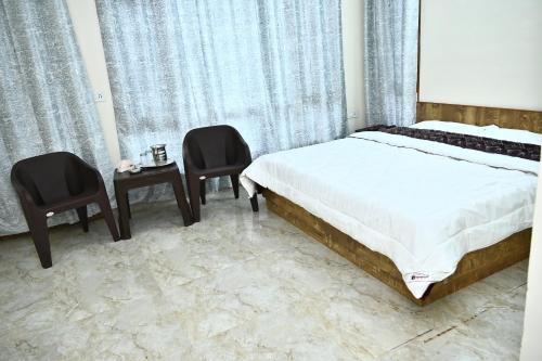 a bedroom with a bed and two chairs and a table at Oakswood B&B in Shimla