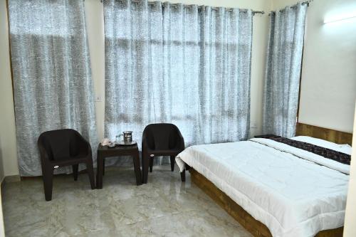 a bedroom with a bed and two chairs and a table at Oakswood B&B in Shimla