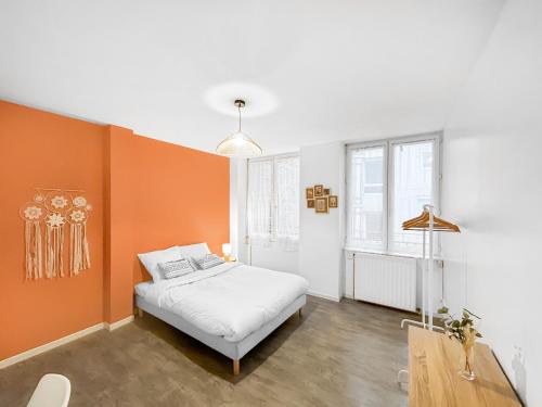 - une chambre avec un mur d'accent orange et un lit dans l'établissement L'Empreinte Stéphanoise, à Saint-Étienne