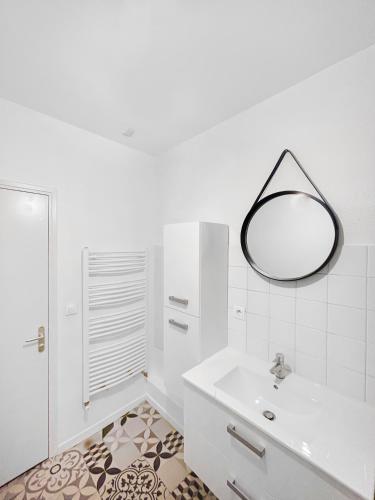 une salle de bain blanche avec un lavabo et un miroir dans l'établissement L'Empreinte Stéphanoise, à Saint-Étienne