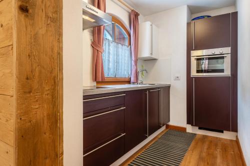 a kitchen with brown cabinets and a window at Dolomitc Tobià in Campitello di Fassa