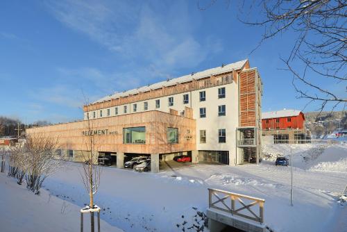 a building in the snow in front of a building at Hotel Element in Lipno nad Vltavou