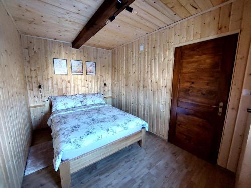 a bed in a wooden room with a wooden door at Holiday home The Hive in Slunj
