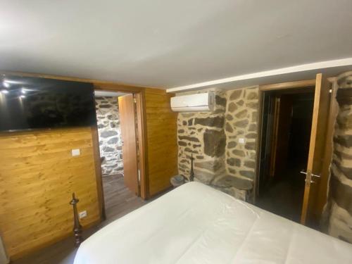 1 dormitorio con cama y pared de piedra en Casa Rosmaninho - Izei, en Chaves