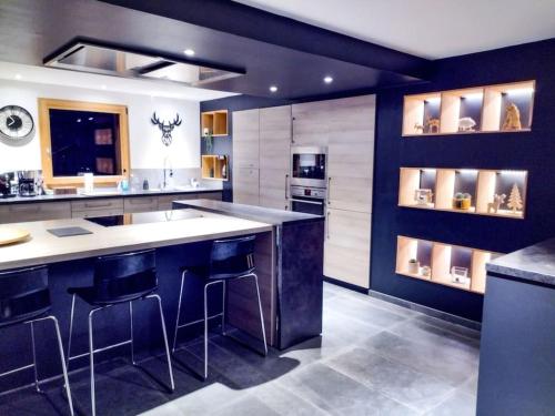 a kitchen with a large island with bar stools at Chalet spacieux & spa in Landry