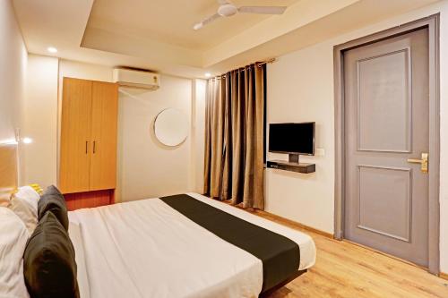 a bedroom with a bed and a tv and a door at Super OYO Townhouse 141 Sector 14 Old Gurgaon in Gurgaon