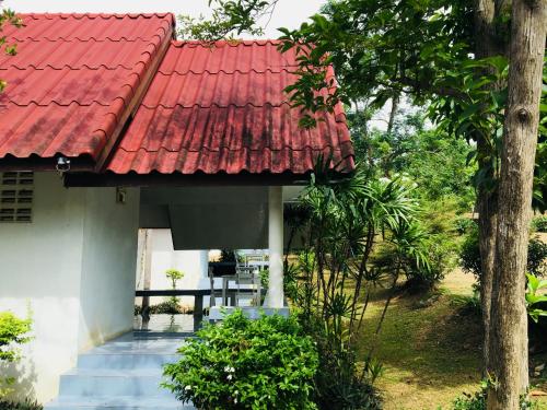 un techo rojo en una casa blanca con escaleras en LungYod guesthouse, en Ban Tha Ling Lom
