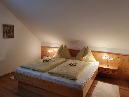 een slaapkamer met een groot bed met witte lakens en kussens bij Appartements Claudia in Mauterndorf