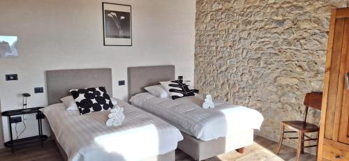 a bedroom with two beds and a stone wall at Agriturismo La Pina in Tarzo