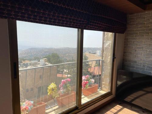 a window with a view of a balcony with flowers at Horizon Villa in Amman