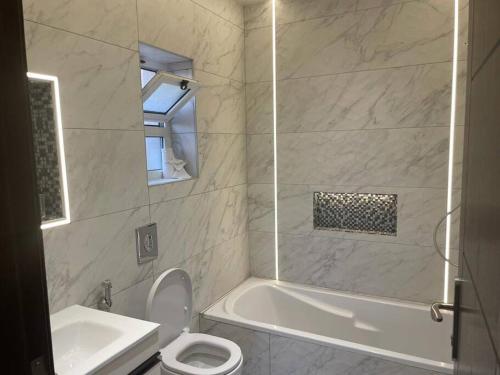 a bathroom with a tub and a toilet and a sink at Horizon Villa in Amman