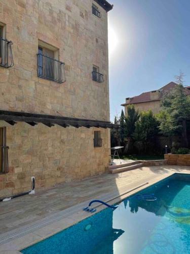 a swimming pool in front of a stone building at Horizon Villa in Amman