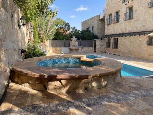 a swimming pool with a fountain in front of a building at Horizon Villa in Amman