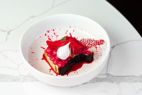 a white bowl with a piece of cake with red toppings at Movenpick Hotel Tallinn in Tallinn