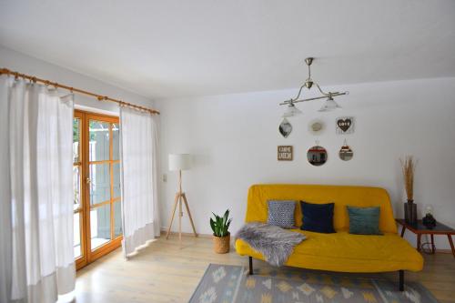 a living room with a yellow couch and a window at Calm GaP in Garmisch-Partenkirchen