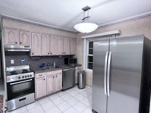 a kitchen with a stainless steel refrigerator and cabinets at Modern and spacious 4 B/R + 2 bath house in Westbury