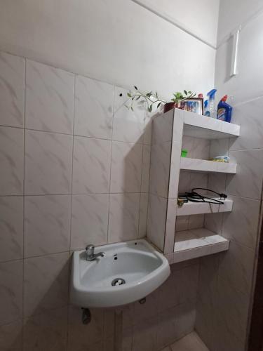 a bathroom with a sink in a white tiled wall at The Gardenview in Guwahati