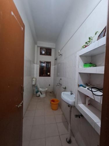 a white bathroom with a toilet and a sink at The Gardenview in Guwahati