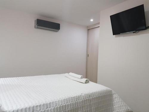 Habitación blanca con cama y TV de pantalla plana. en Hotel Valledupar Plaza, en Valledupar
