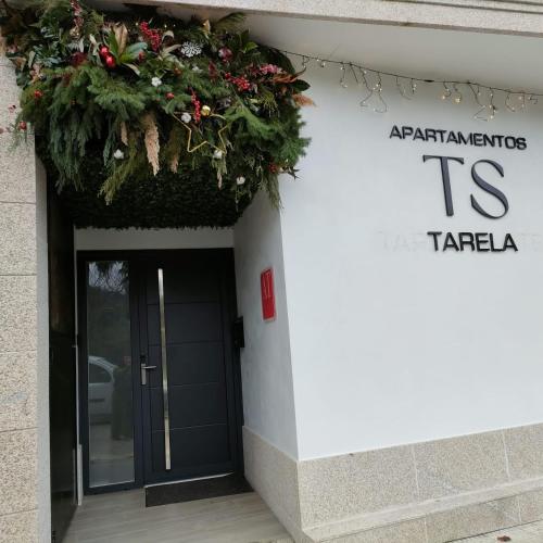 a sign on the side of a building with a plant at Apartamentos TARELA Porriño in Porriño