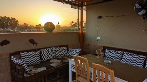 een restaurant met een tafel en stoelen met uitzicht op de zonsondergang bij Yasmine Guest House in Luxor