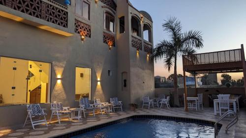 a house with a swimming pool and tables and chairs at Yasmine Guest House in Luxor