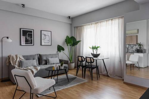 uma sala de estar com um sofá, uma mesa e cadeiras em Your Cosy Perch in the Heart of the Athenian Buzz em Atenas