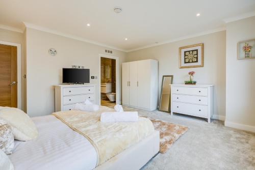 a white bedroom with a large bed and a tv at Concord House in Brentford