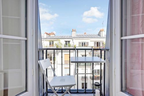 d'un balcon avec une chaise blanche et une vue sur un bâtiment. dans l'établissement Modern apartment - 2BR-4P - Sacré-Cœur, à Paris